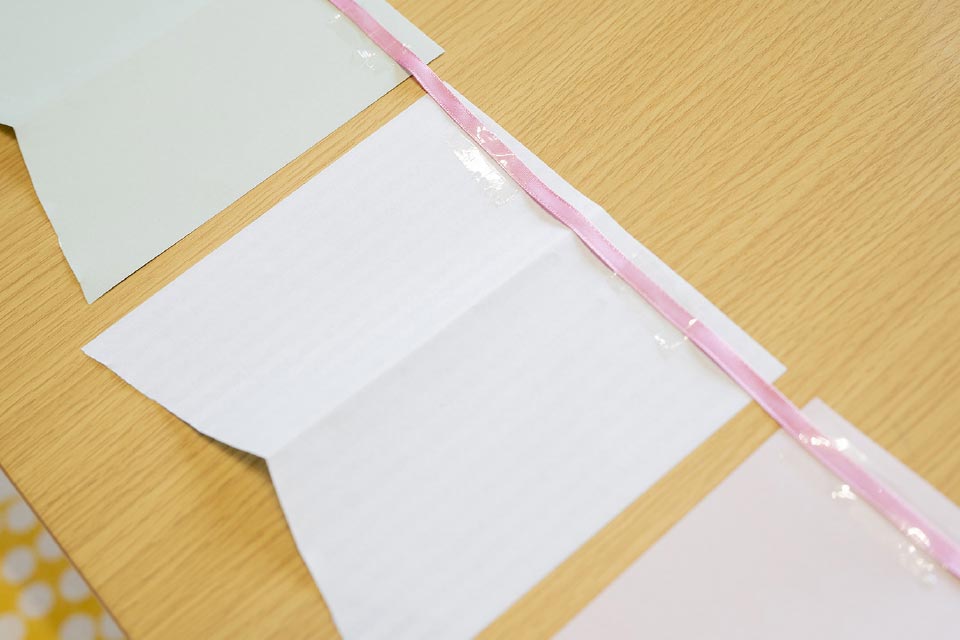 (2)を開いて裏面を上にして、好きな順番にカーブをつけて並べ、全体にひもをテープでつける。