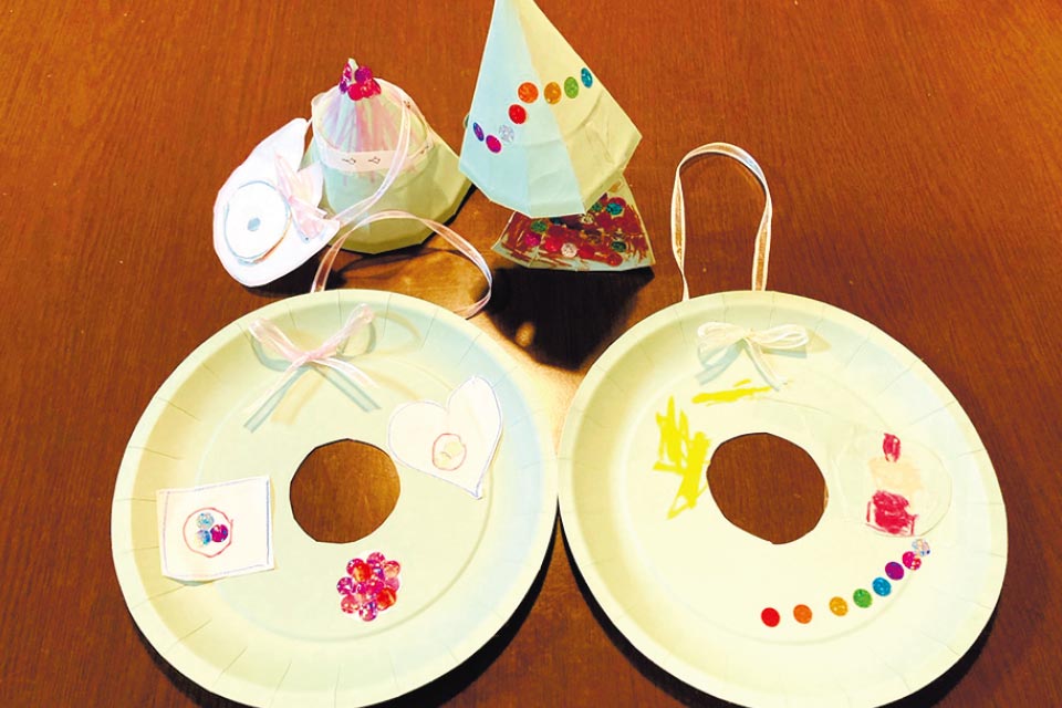 紙皿の真ん中を丸く切り抜き、シールやリボンで飾り付けるクリスマスリース